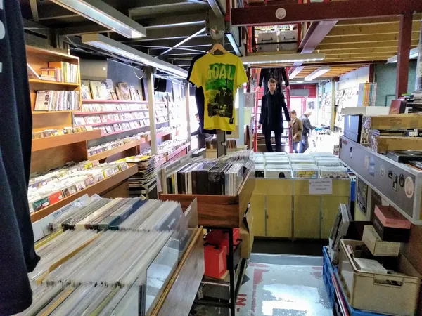 Het interieur van De Plaatboef Rotterdam: gangpaden vol platenbakken en cd's aan de muren.